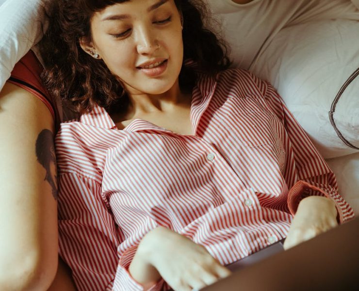 woman using a laptop and reclining on her girlfriend