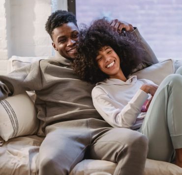 beloved african american couple cuddling and smiling on couch