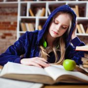 woman wearing blue jacket sitting on chair near table reading books