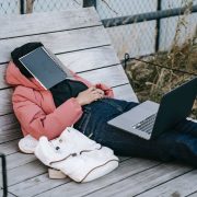 unrecognizable woman with laptop resting on bench in park