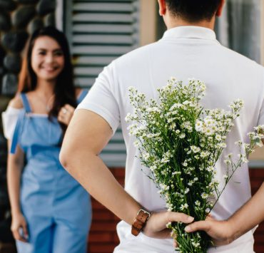 man holding baby s breath flower in front of woman standing near marble wall