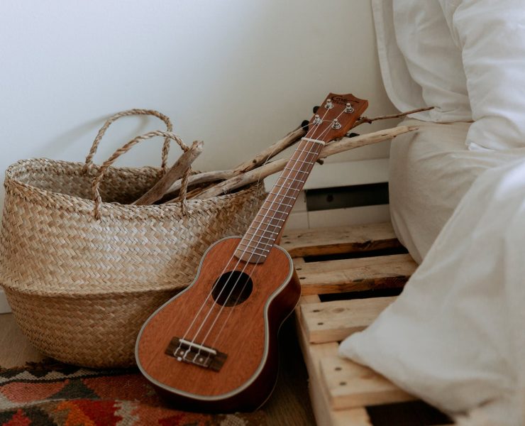interior with wooden branches in wicker basket and small guitar near bed