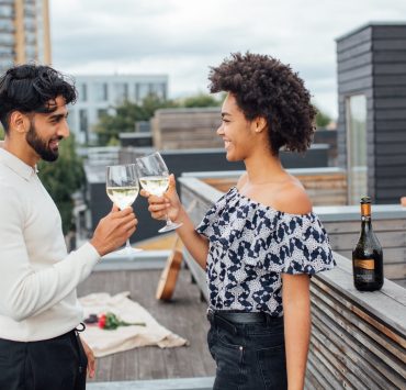 a couple toasting their glasses with white wine