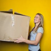 woman in grey shirt holding brown cardboard box