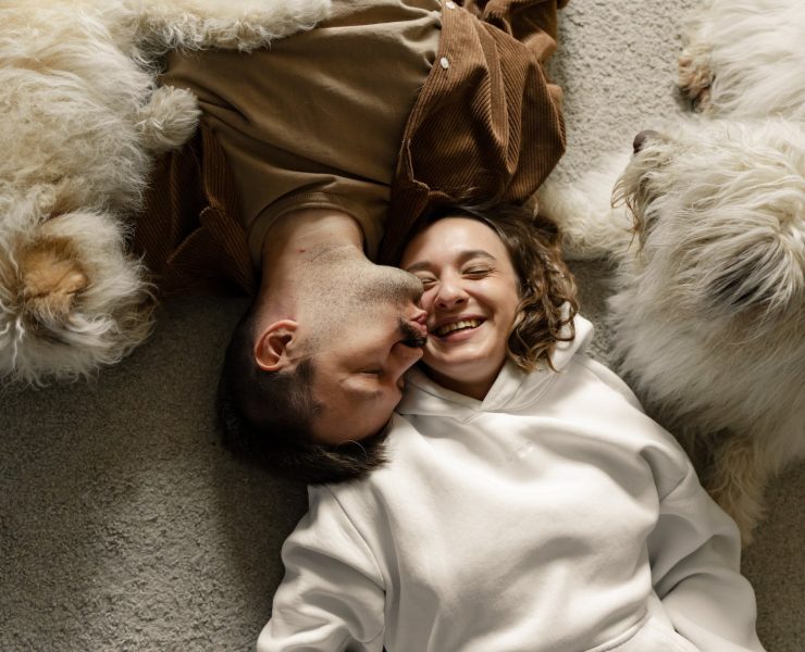 couple lying on the carpet with their dogs