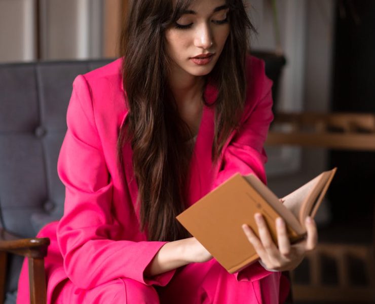woman wearing pink suit reading a book